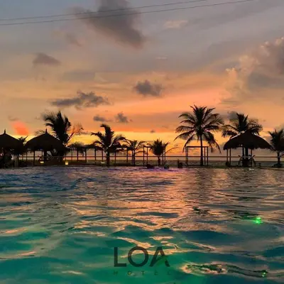 a sunset on a beach with palm trees and the ocean at Loa Tolú by Bernalo Hotels in Tolú