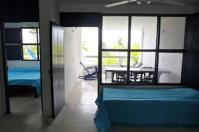 a room with a bed and a table and windows at Apartamentos Las Múcuras in Coveñas