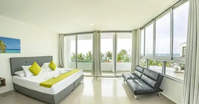 a bedroom with a bed and a chair and windows at Green Coveñas by Bernalo Hotels in Coveñas