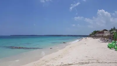 a beach with chairs and umbrellas and the ocean at Pura Vida Baru - La Casa del Cholo in Baru