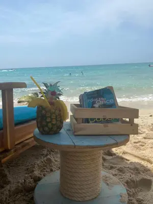 a table with a pineapple and a book on the beach at Pura Vida Baru - La Casa del Cholo in Baru
