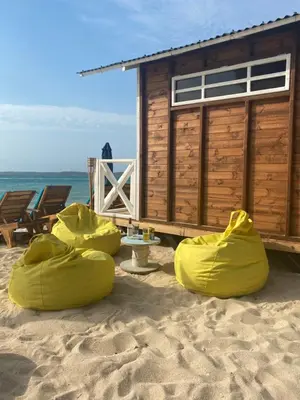 a beach shack with yellow covers on the sand at Pura Vida Baru - La Casa del Cholo in Baru