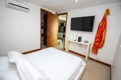 a bedroom with a white bed and a flat screen tv at Excelente Apartamento Palmetto con vista al mar in Cartagena de Indias