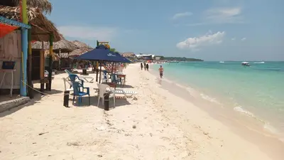 a beach with chairs and tables and the ocean at Cabaña Luna Azul in Playa Blanca