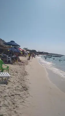 a beach with people sitting on chairs and umbrellas at Cabaña Luna Azul in Playa Blanca