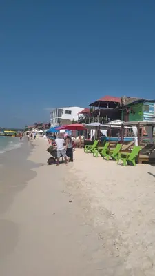 a beach with green chairs and people on the sand at Cabaña Luna Azul in Playa Blanca
