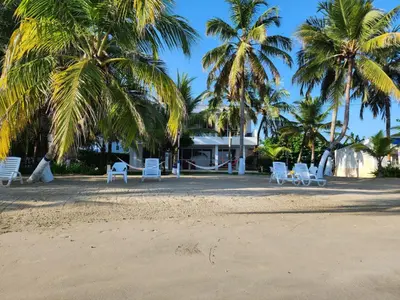 a group of white chairs on a beach with palm trees at Condominio Milagros Coveñas in Coveñas
