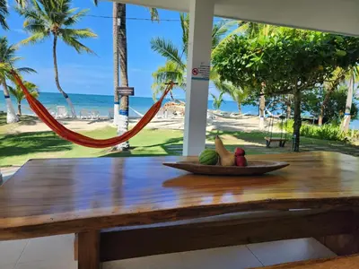 a table with a bowl of fruit and a hammock on a beach at Condominio Milagros Coveñas in Coveñas