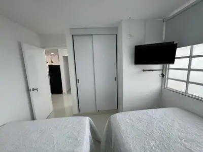 a bedroom with two beds and a flat screen tv at Apartamento Vista Lateral a la Playa By ICDI in Cartagena de Indias