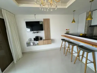 a kitchen with a bar with stools and a television at Apartamento Vista Lateral a la Playa By ICDI in Cartagena de Indias