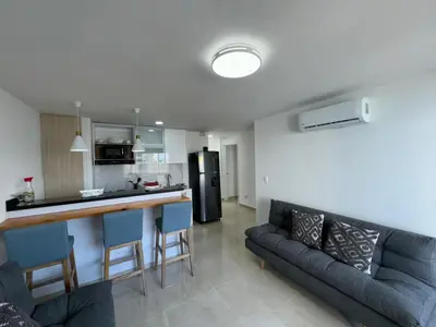 a kitchen and a living room with a couch and a counter at Apartamento Vista Lateral a la Playa By ICDI in Cartagena de Indias
