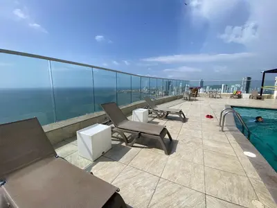 a balcony with chairs and a swimming pool on a building at Apartamento Frenta a la Playa in Cartagena de Indias