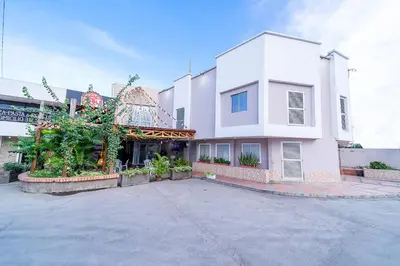 a large white building with a parking lot at Hotel Baly Express in Malambo