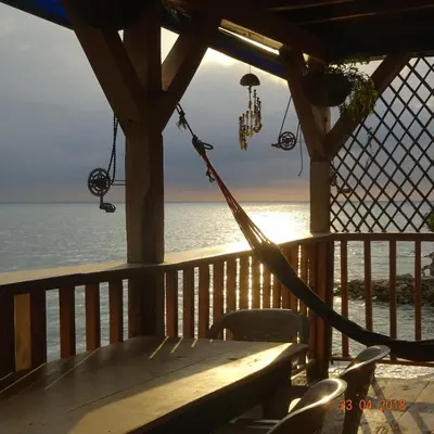 a hammock on a porch overlooking the ocean at Hostel Blue Sea Rincon del Mar in Rincón