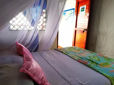 a bedroom with a bed with a canopy and a window at Hostel Blue Sea Rincon del Mar in Rincón