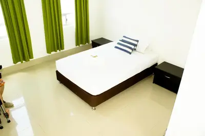a bed in a room with green curtains at Hotel Las Olas Mamonal in Cartagena de Indias