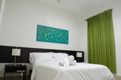 a bedroom with a white bed with a green curtain at Hotel Las Olas Mamonal in Cartagena de Indias
