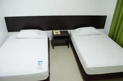 two twin beds in a room with a desk at Hotel Las Olas Mamonal in Cartagena de Indias