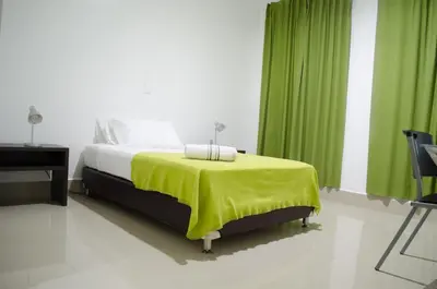a bedroom with a bed with a green curtain at Hotel Las Olas Mamonal in Cartagena de Indias