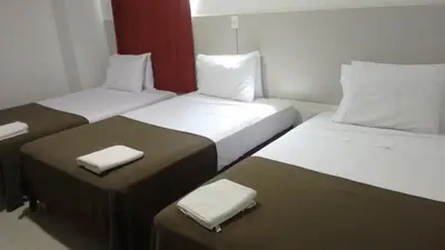 two beds in a hotel room with white sheets at Hotel las Olas Malambo in Malambo