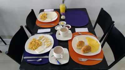 a table with plates of food and cups of coffee at Hotel Cosmos Sincelejo in Sincelejo