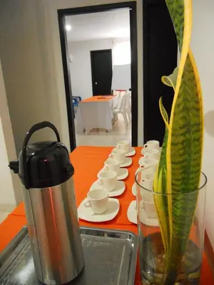 a table with a coffee pot and a vase with a plant at Hotel Cosmos Sincelejo in Sincelejo