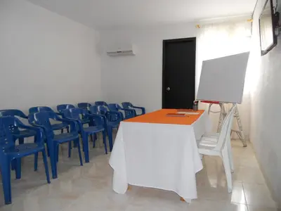 a conference room with a white table and blue chairs at Hotel Cosmos Sincelejo in Sincelejo