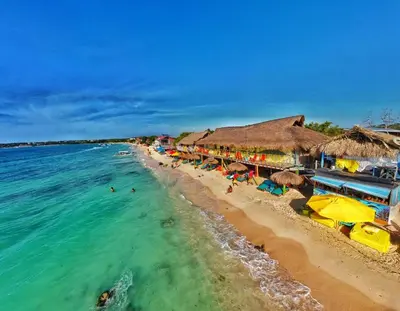 a beach with umbrellas and people swimming in the ocean at Nuestros Tres Tesoros II in Playa Blanca