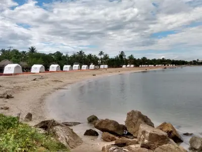 a beach with white tents and rocks in the water at Hostal Santa Clara in San Antero
