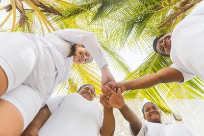 a group of people holding hands under a palm tree at Hotel Sunset Beach in Cartagena de Indias