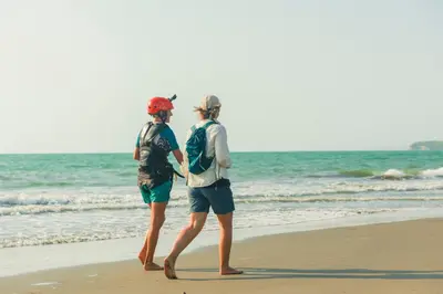 two people walking on the beach near the ocean at Hotel Sunset Beach in Cartagena de Indias