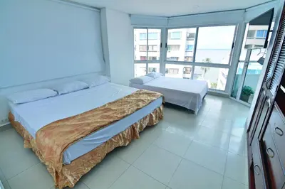 a bedroom with two beds and a large window at Torres del Lago Apartamentos in Cartagena de Indias