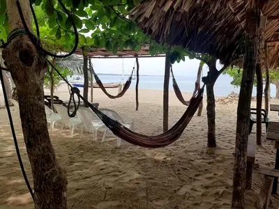 a hammock on a beach with chairs and the ocean at Casa Madrigueña in Rincón