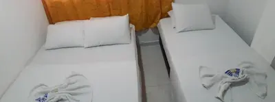 two beds in a room with white sheets and pillows at Hotel Torres del Parque No3 in Barranquilla
