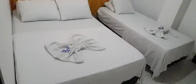 two beds with white sheets and towels on them at Hotel Torres del Parque No3 in Barranquilla