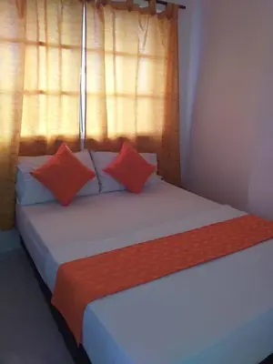 a bed with orange and white pillows in a room at Hotel Torres del Parque No3 in Barranquilla