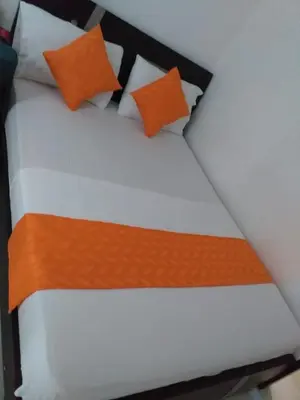 a bed with orange and white pillows on it at Hotel Torres del Parque No3 in Barranquilla