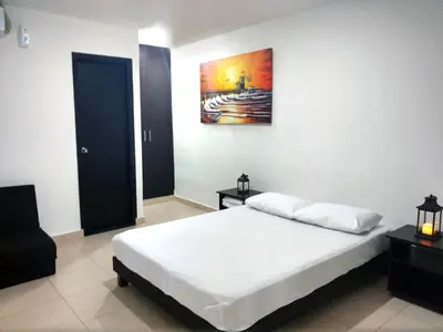 a bedroom with a bed and a painting on the wall at Hotel El Emigrante in Puerto Colombia