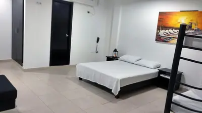 a bedroom with a bed and a painting on the wall at Hotel El Emigrante in Puerto Colombia