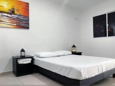a bedroom with a bed with two night stands and two lamps at Hotel El Emigrante in Puerto Colombia