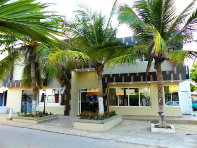 two palm trees in front of a building at Hotel El Emigrante in Puerto Colombia