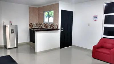 a kitchen with a red chair and a refrigerator at Hotel El Emigrante in Puerto Colombia