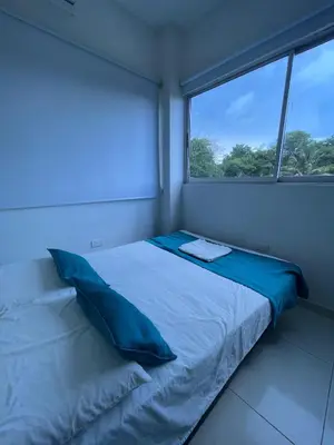 a bedroom with a bed with blue pillows and a window at Cabanas Villa Antonella Covenas in Coveñas