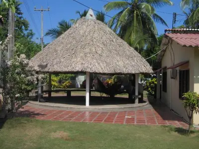 a pavilion with a straw roof in a yard at Hostal Roldan in Coveñas