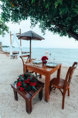 a table with chairs and an umbrella on the beach at Hotel Islabela Islas Del Rosario in Isla Grande