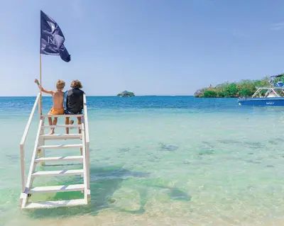 two people standing on a ladder in the water on a dock at Hotel Islabela Islas Del Rosario in Isla Grande