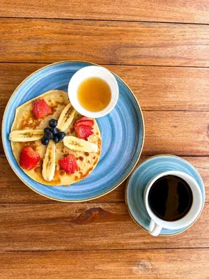 a plate of pancakes with fruit and a cup of coffee at Hotel Islabela Islas Del Rosario in Isla Grande