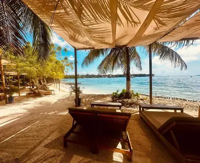 a beach with two tables and chairs and the ocean at Hotel Islabela Islas Del Rosario in Isla Grande