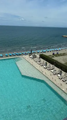 a swimming pool with chairs and umbrellas and the beach at Namaste Alojamientos Luxury Cartagena in Cartagena de Indias