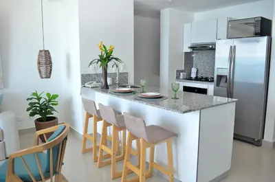a kitchen with a counter with chairs and a refrigerator at Namaste Alojamientos Luxury Cartagena in Cartagena de Indias